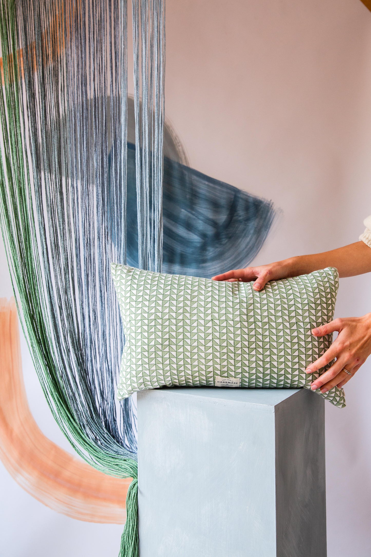 A small rectangular cushion with a green and cream triangle pattern on