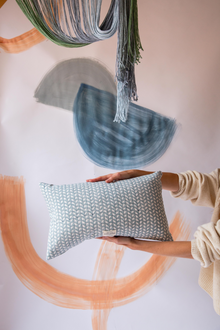  Someone holding a blue rectangular cushion with a triangle pattern on
