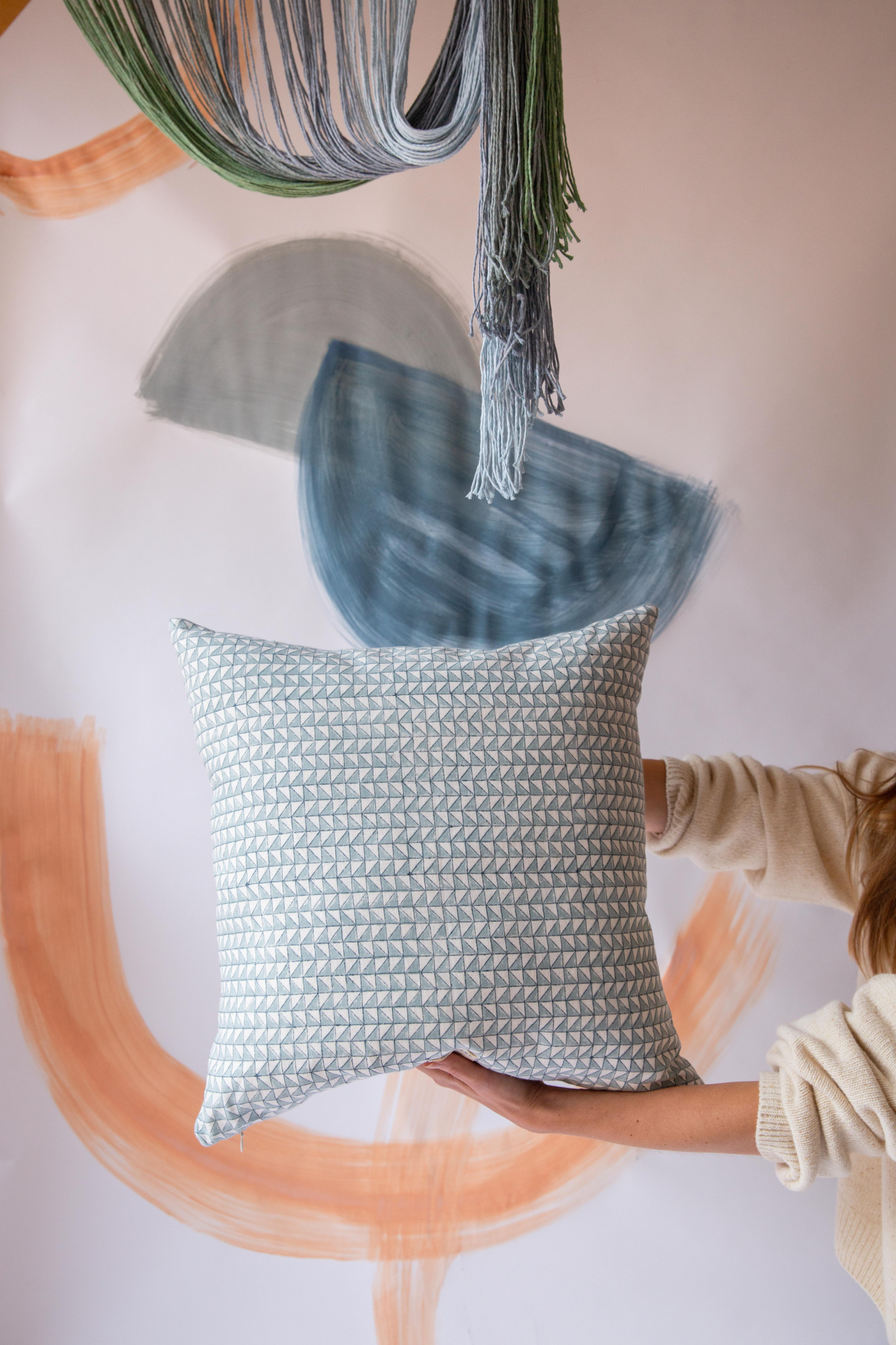 Someone holding a blue square cushion with a triangle pattern on