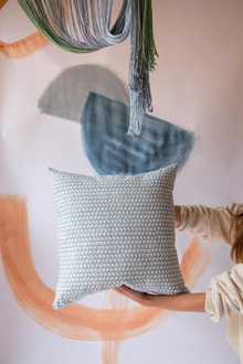  Someone holding a blue square cushion with a triangle pattern on