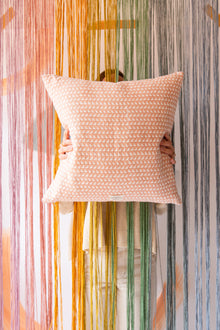  Someone holding a pink square cushion with a triangle pattern on