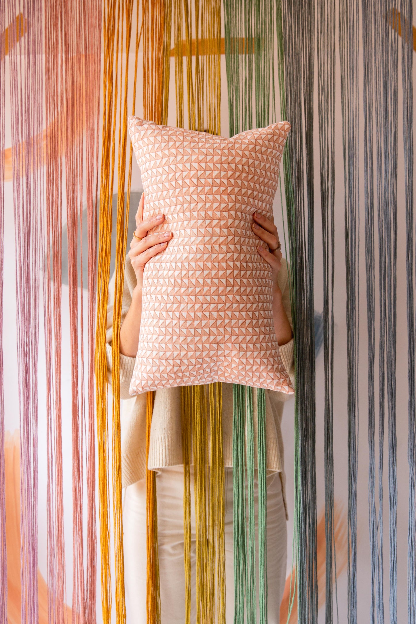 Someone holding a pink rectangular cushion with a triangle pattern on