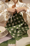 Woman tucking pink and green napkin into the front of her blouse