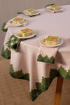 Four folded pink napkins with green trim and one mostly green each with a plate of cake on top of it