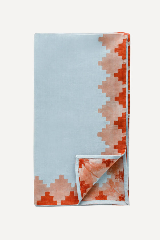 Blue tablecloth with red trim folded into a rectangle with one corner turned over